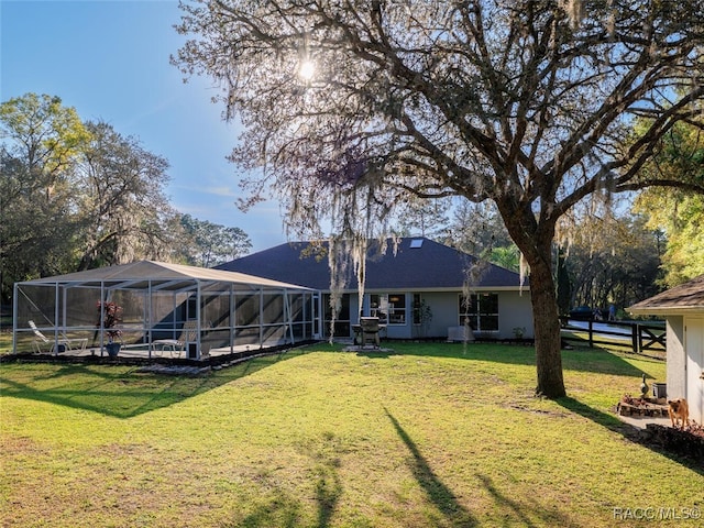 rear view of house featuring a lawn and glass enclosure