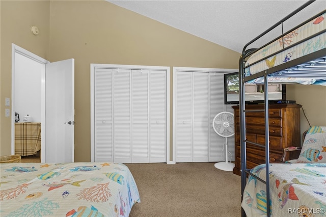 carpeted bedroom with vaulted ceiling, a textured ceiling, and two closets