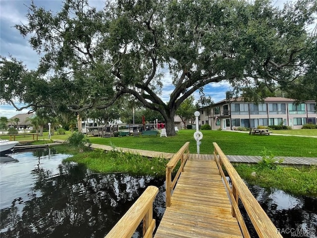 dock area with a lawn and a water view