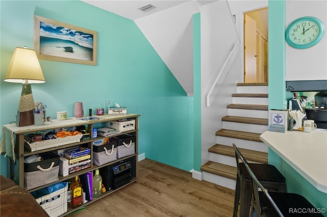 stairs featuring hardwood / wood-style floors and vaulted ceiling