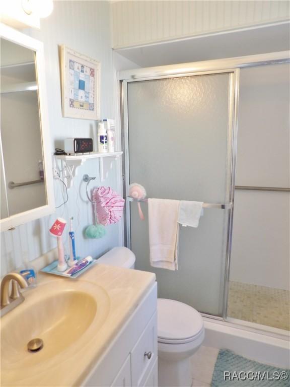 bathroom featuring tile patterned flooring, vanity, an enclosed shower, and toilet