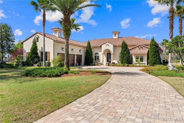 12380 SW 140th Loop, Dunnellon, FL 34432 - mediterranean / spanish-style home with curved driveway, stucco siding, an attached garage, a front yard, and a tiled roof