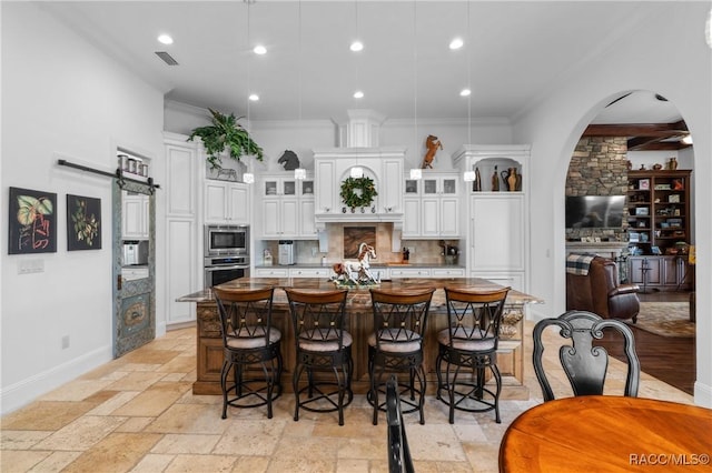 12380 SW 140th Loop, Dunnellon, FL 34432 - kitchen with appliances with stainless steel finishes, a large island with sink, stone tile floors, ornamental molding, and tasteful backsplash