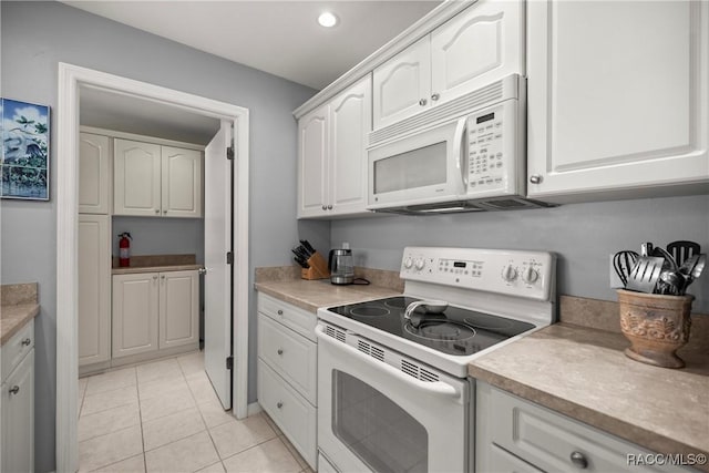 kitchen featuring white cabinetry, light tile patterned floors, and white appliances