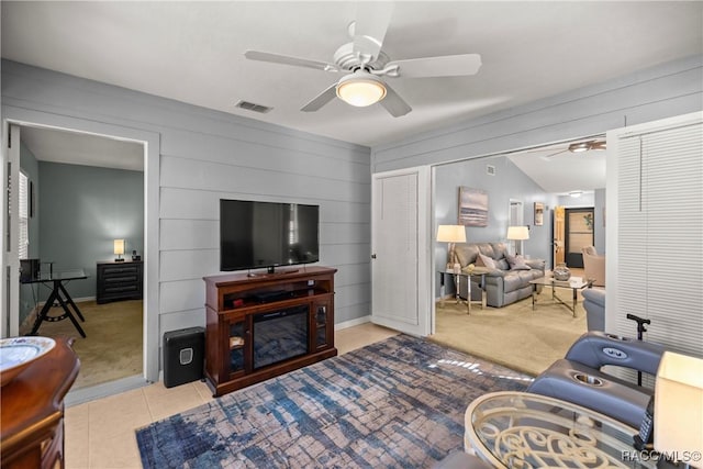 living room featuring wooden walls, vaulted ceiling, ceiling fan, and light tile patterned flooring