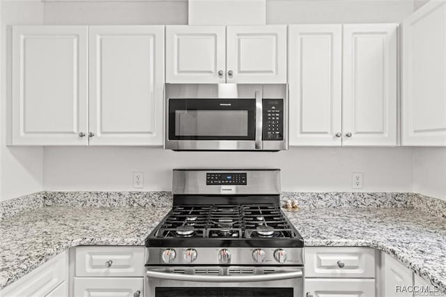 kitchen with appliances with stainless steel finishes, light stone countertops, and white cabinets