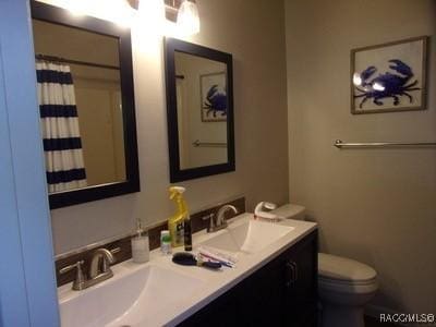 bathroom featuring vanity, curtained shower, and toilet