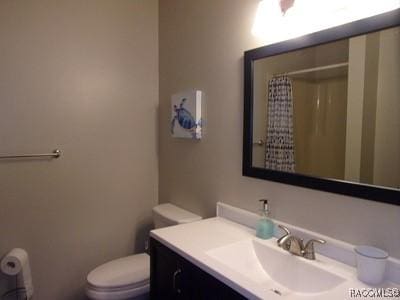 bathroom with a shower with curtain, vanity, and toilet