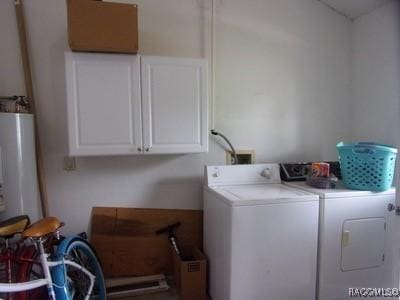 laundry room featuring cabinets, washing machine and clothes dryer, and water heater