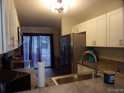 kitchen with white cabinetry, sink, stainless steel refrigerator with ice dispenser, and range