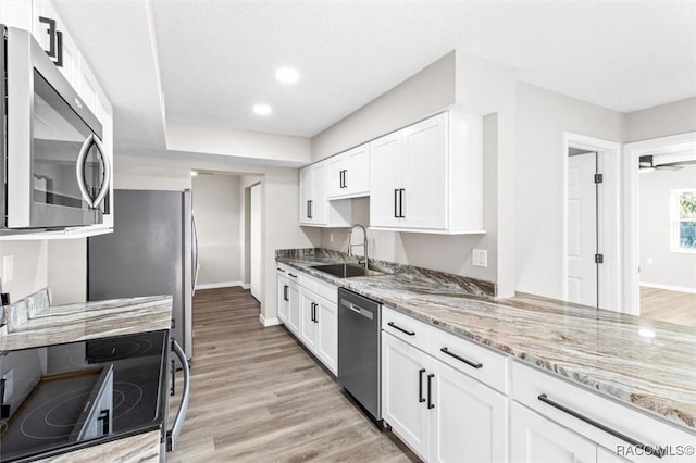 kitchen featuring appliances with stainless steel finishes, light hardwood / wood-style floors, sink, and white cabinets