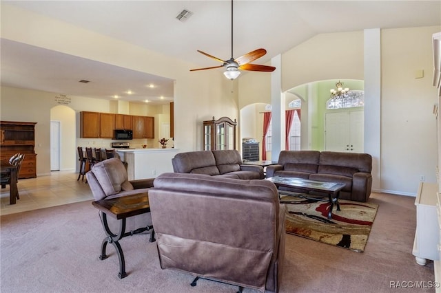 living room with ceiling fan with notable chandelier, light colored carpet, and vaulted ceiling