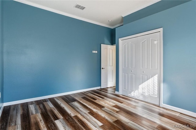 unfurnished bedroom with hardwood / wood-style flooring, a closet, and ornamental molding