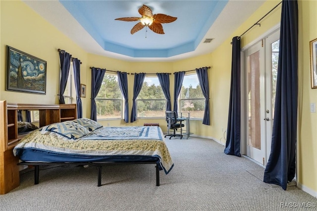 bedroom with ceiling fan, a raised ceiling, and carpet floors