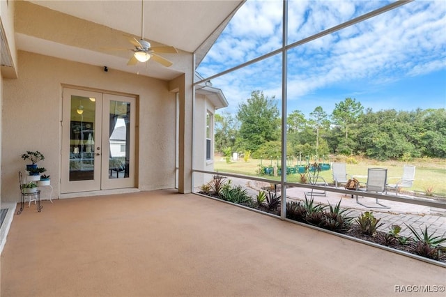 unfurnished sunroom featuring ceiling fan and french doors