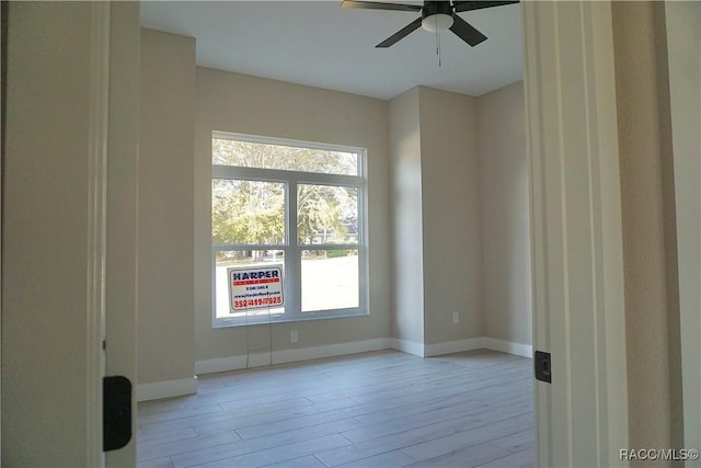 unfurnished room with baseboards, light wood-style floors, and a ceiling fan