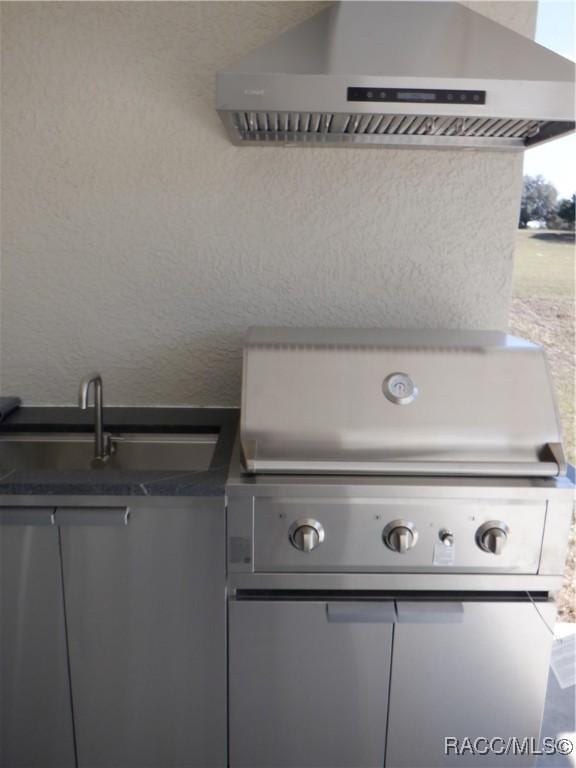 exterior details with wall chimney exhaust hood and a sink