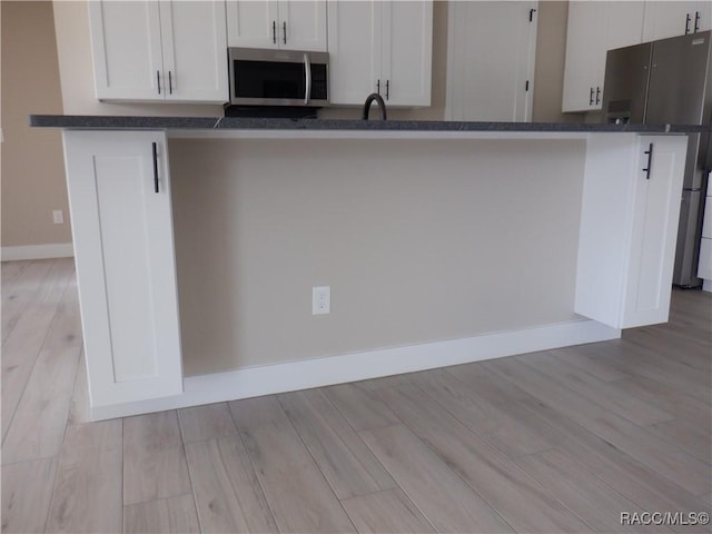 786 E Dunbar Ln, Hernando, FL 34442 - kitchen with appliances with stainless steel finishes, light wood-style flooring, white cabinets, and dark stone countertops