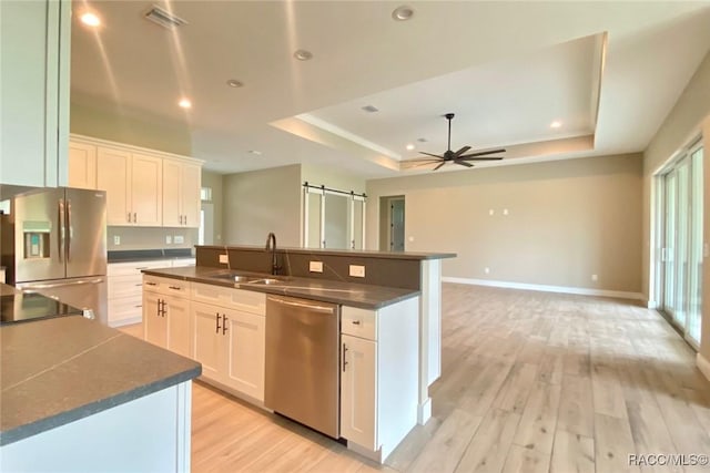 786 E Dunbar Ln, Hernando, FL 34442 - kitchen featuring appliances with stainless steel finishes, a tray ceiling, dark countertops, a center island with sink, and light wood-style flooring