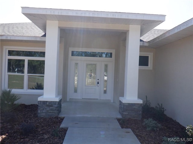 property entrance featuring stucco siding and roof with shingles