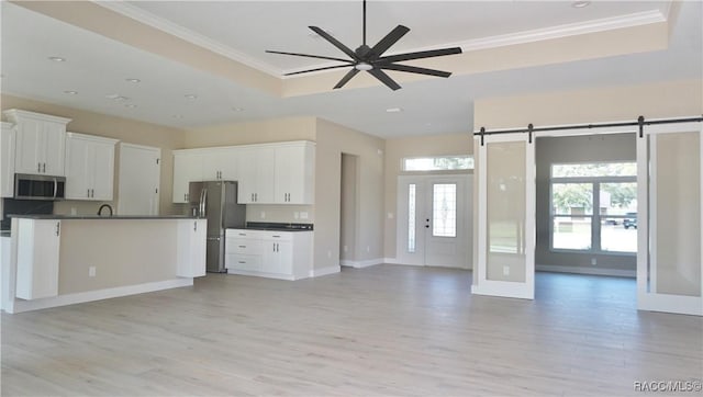 kitchen with a raised ceiling, dark countertops, appliances with stainless steel finishes, and open floor plan