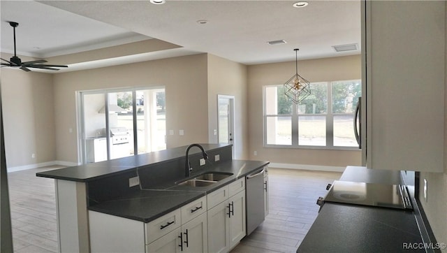 kitchen with a center island with sink, a sink, stainless steel dishwasher, dark countertops, and open floor plan