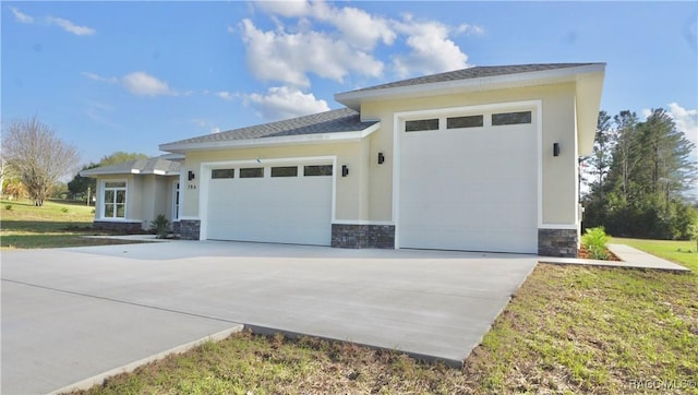 view of front of home with a garage, stone siding, concrete driveway, and stucco siding