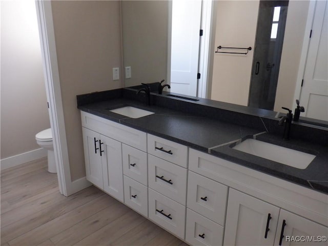 full bath featuring toilet, wood finished floors, and a sink