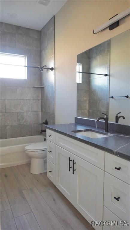 bathroom with vanity, shower / bathing tub combination, toilet, and wood finished floors