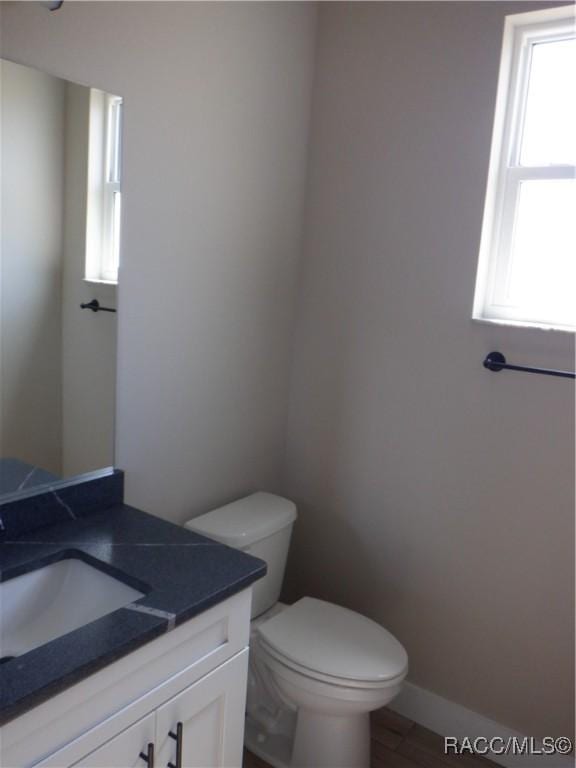 bathroom with baseboards, toilet, wood finished floors, and vanity