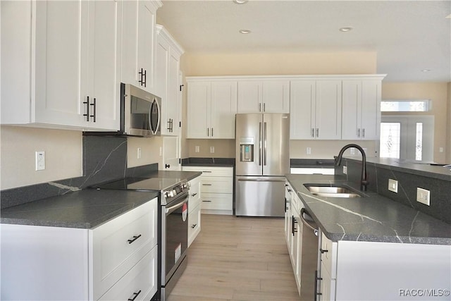 kitchen with light wood-style flooring, recessed lighting, a sink, white cabinets, and appliances with stainless steel finishes