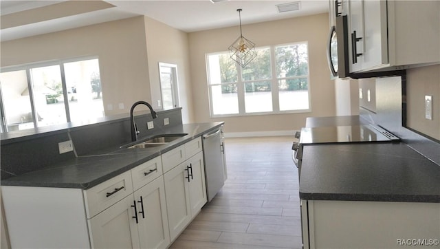 kitchen featuring visible vents, stainless steel appliances, a sink, white cabinetry, and dark countertops