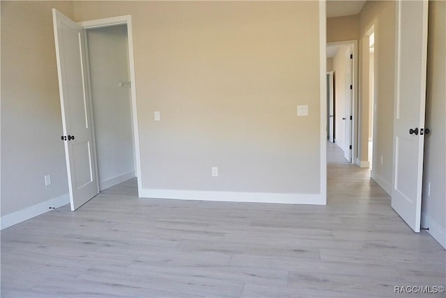 spare room featuring baseboards and light wood-style flooring