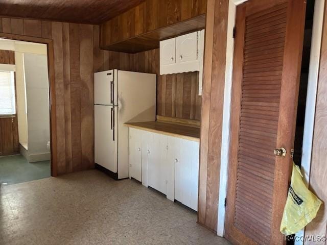 kitchen with wood walls and freestanding refrigerator