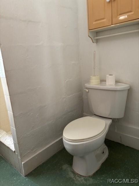 bathroom with a tile shower and toilet