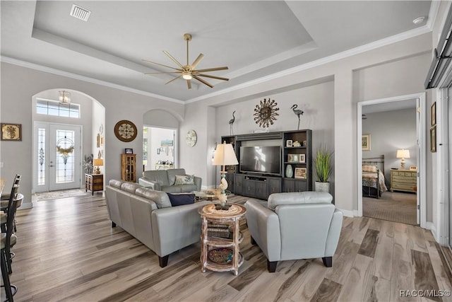 living room featuring ceiling fan, a raised ceiling, ornamental molding, and light hardwood / wood-style flooring