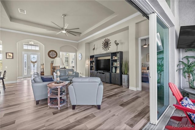 living room featuring ceiling fan, light hardwood / wood-style floors, a raised ceiling, and ornamental molding