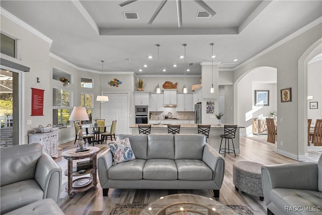 living room featuring ornamental molding, a tray ceiling, and light hardwood / wood-style flooring