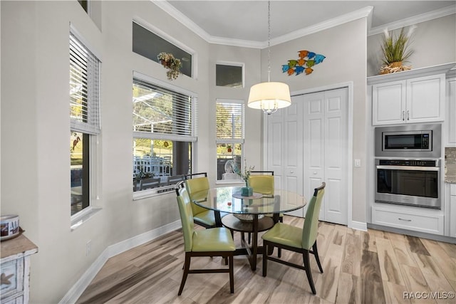 dining area with a towering ceiling, light hardwood / wood-style floors, and ornamental molding