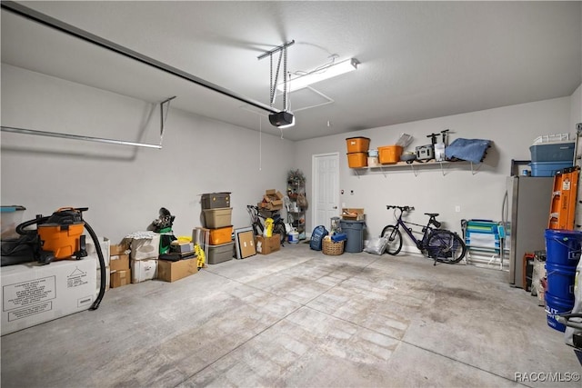 garage with stainless steel fridge and a garage door opener