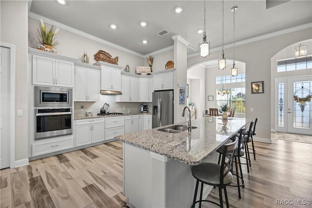 kitchen featuring a large island, sink, light hardwood / wood-style flooring, white cabinets, and appliances with stainless steel finishes