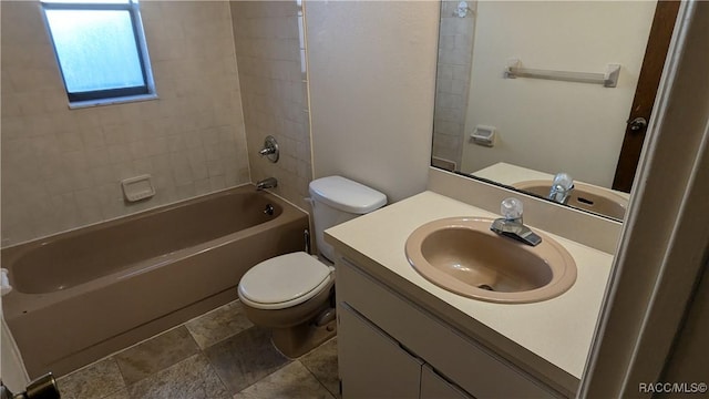 bathroom featuring toilet, vanity, stone finish floor, and shower / bathtub combination