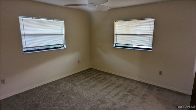 spare room featuring ceiling fan, dark carpet, and baseboards