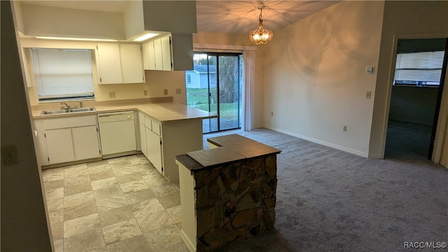 kitchen featuring a peninsula, white dishwasher, white cabinetry, and pendant lighting