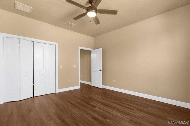 unfurnished bedroom featuring dark hardwood / wood-style flooring, ceiling fan, and a closet