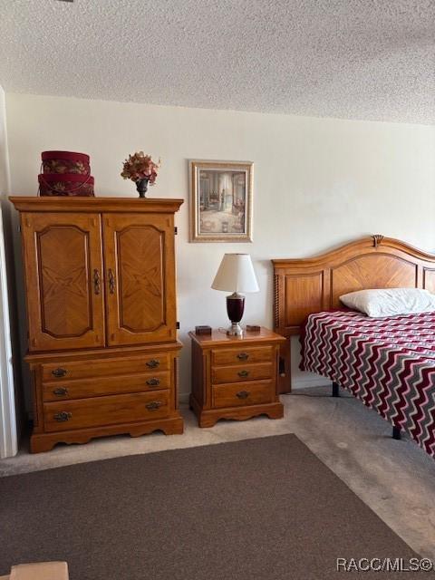 bedroom featuring light colored carpet and a textured ceiling