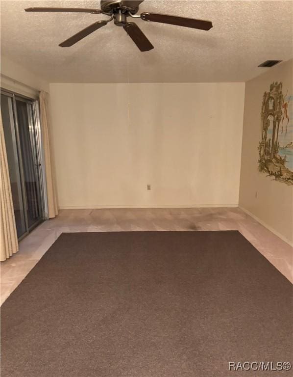 carpeted spare room with a textured ceiling and ceiling fan