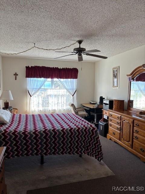 carpeted bedroom featuring multiple windows, ceiling fan, and a textured ceiling