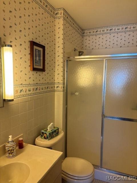 bathroom featuring tile walls, vanity, a shower with door, and toilet