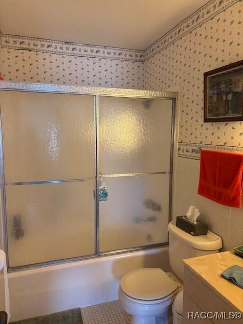 full bathroom featuring tile patterned flooring, bath / shower combo with glass door, vanity, and toilet